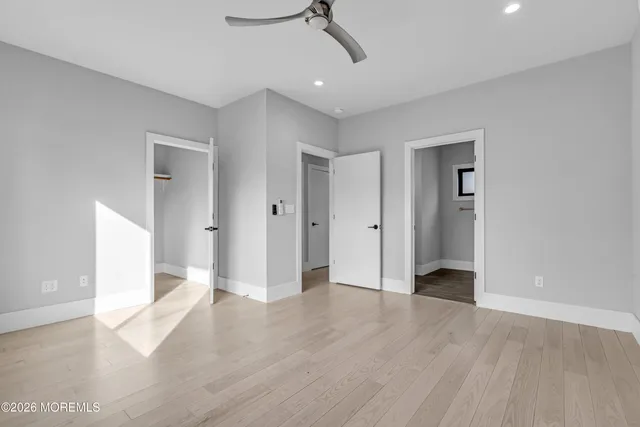 an empty room with wooden floor and ceiling fan