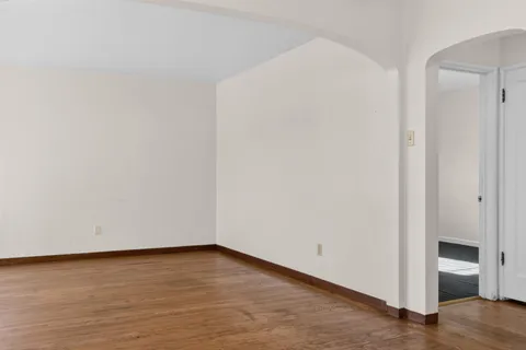 a view of an empty room with wooden floor and closet
