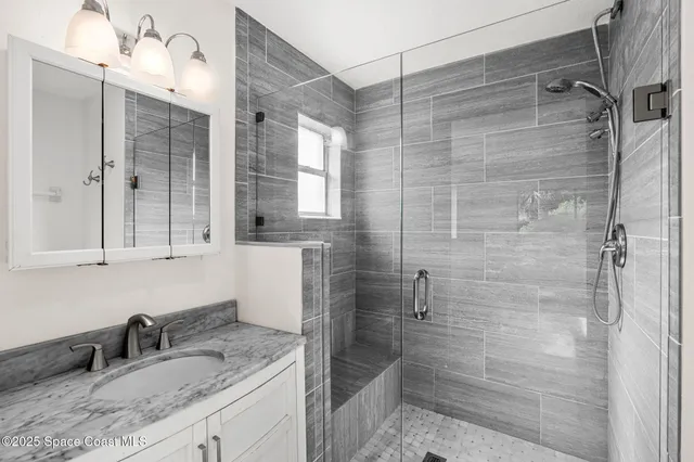 a bathroom with a granite countertop sink a mirror and shower