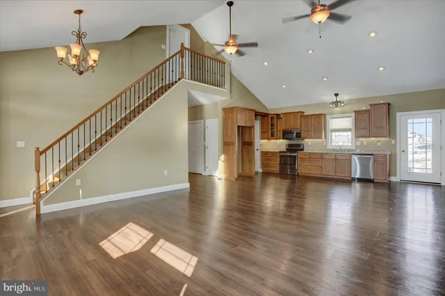 a view of a room with wooden floor staircase and kitchen view