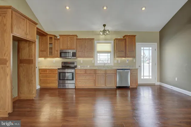 a large kitchen with cabinets wooden floor and stainless steel appliances
