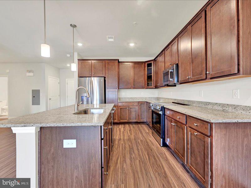 a kitchen with kitchen island granite countertop wooden cabinets and refrigerator