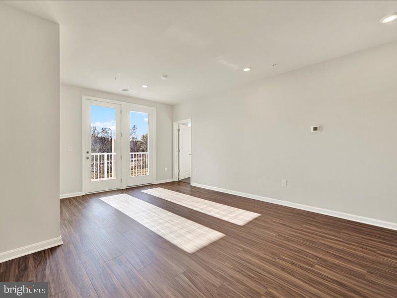 4003 Seaside Alder Road, Unit 308 ROSE Bowie, MD 20720 - Photo 17 of 44 a view of an empty room with wooden floor and a window