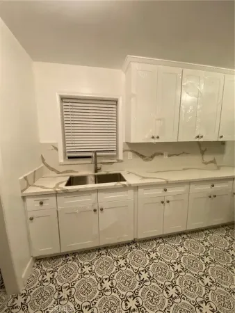 a room with granite countertop cabinets sink and a window
