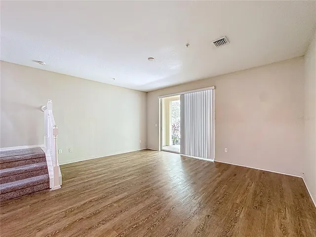 a view of an empty room with wooden floor and closet