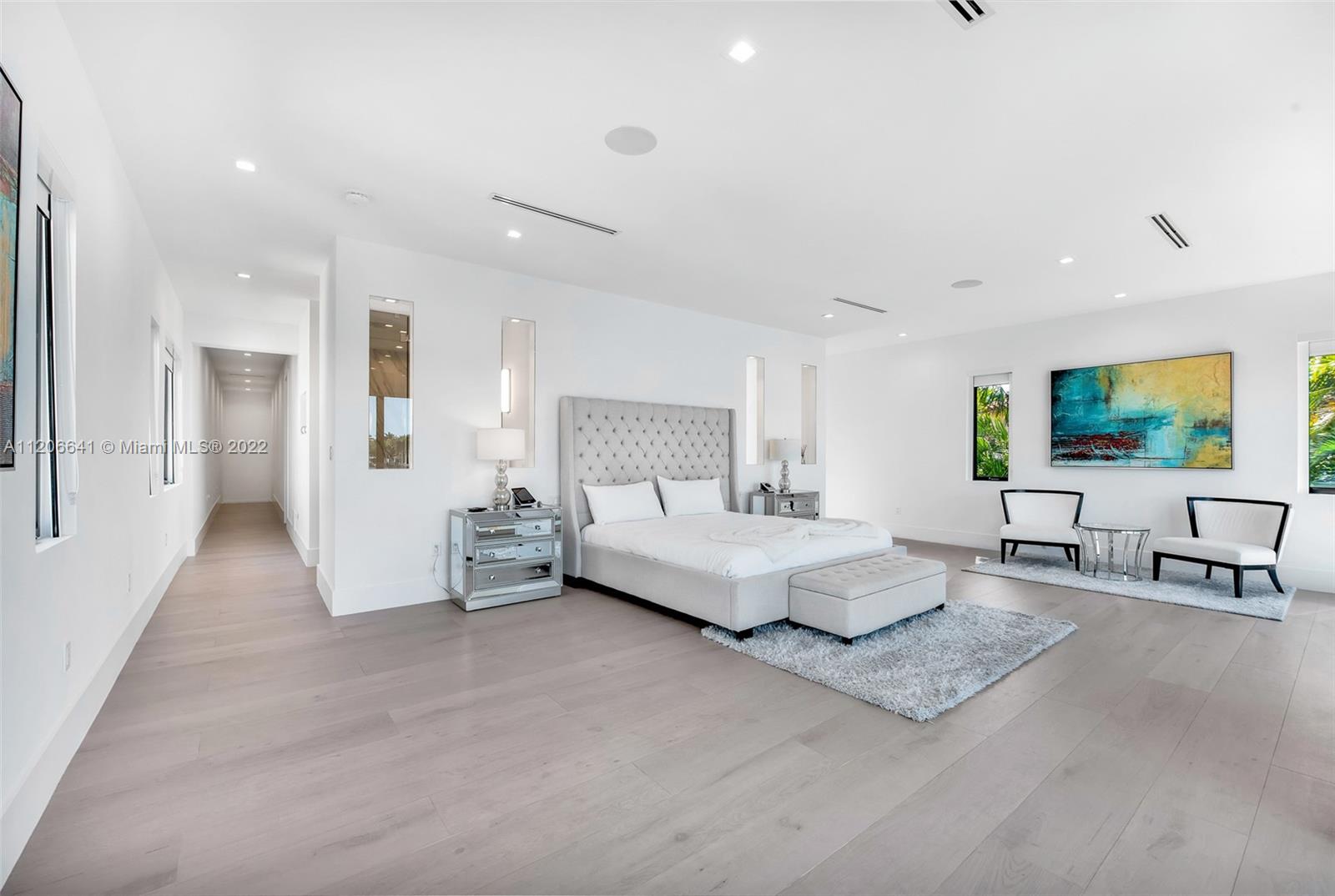 2700 North Bay Road Miami Beach, FL 33140 - Photo 16 of 42 a spacious bedroom with a bed a couch and a flat tv screen on dresser