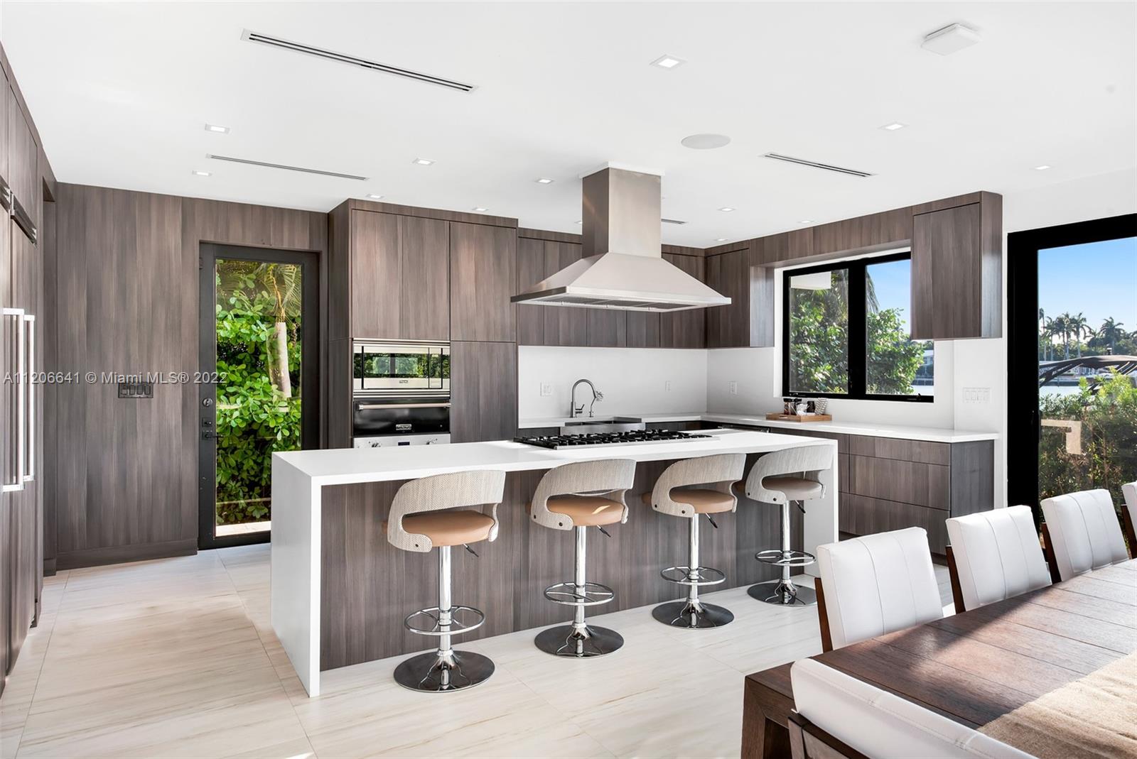 2700 North Bay Road Miami Beach, FL 33140 - Photo 8 of 42 a view of kitchen with stainless steel appliances kitchen island a table chairs in it and wooden floors
