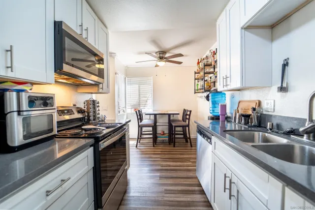 a kitchen with granite countertop a sink dishwasher stove and oven with wooden cabinets