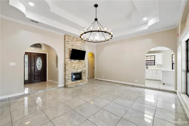 a view of a livingroom with a fireplace a chandelier and windows