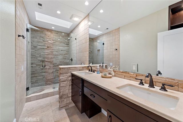a bathroom with a sink double vanity granite tub shower and a mirror