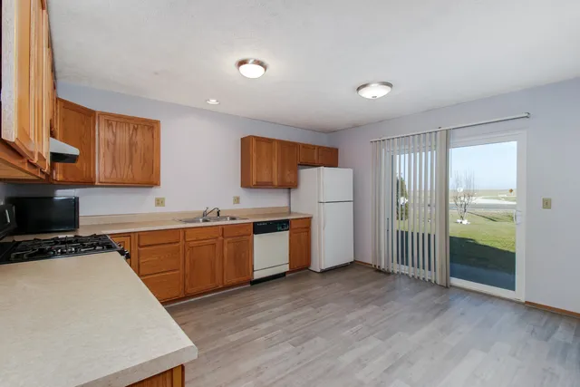 a kitchen with a refrigerator a stove top oven a sink and dishwasher with wooden floor