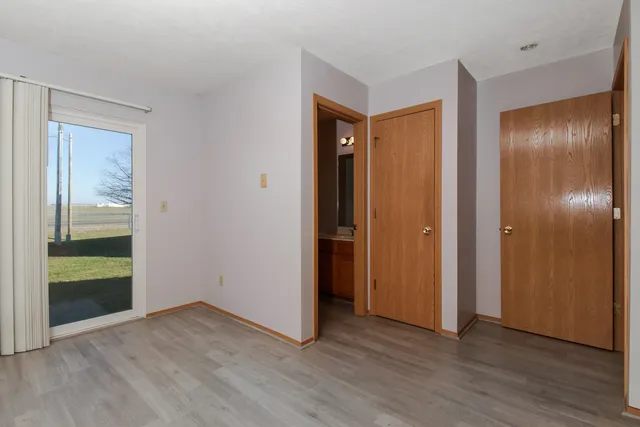 an empty room with wooden floor bathroom and front door
