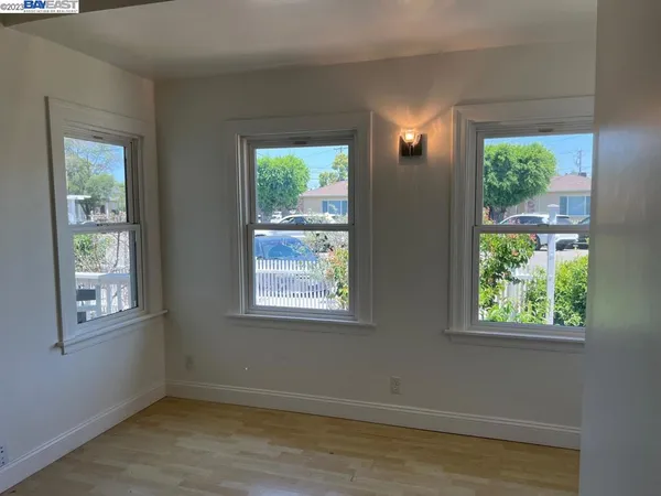 a view of an empty room with wooden floor and windows