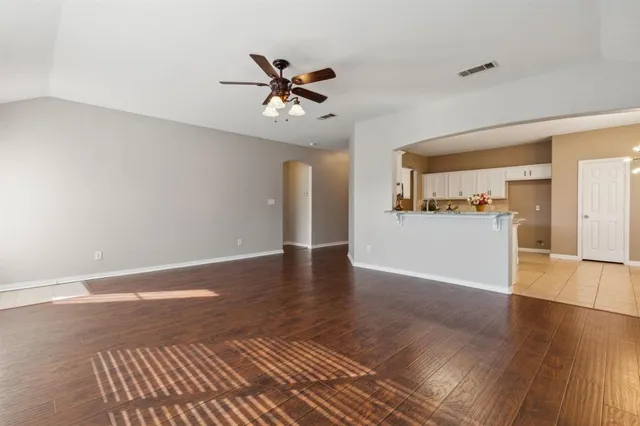a view of a livingroom with wooden floor and kitchen space