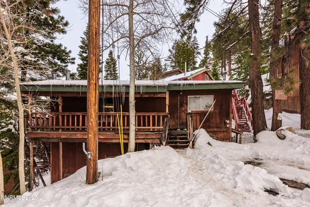 a view of a wooden house with a large trees and wooden fence