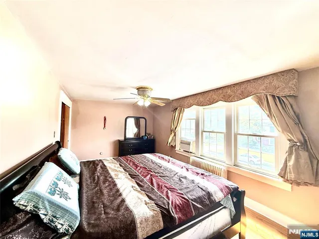 a bedroom with a bed and a flat tv screen next to a large window