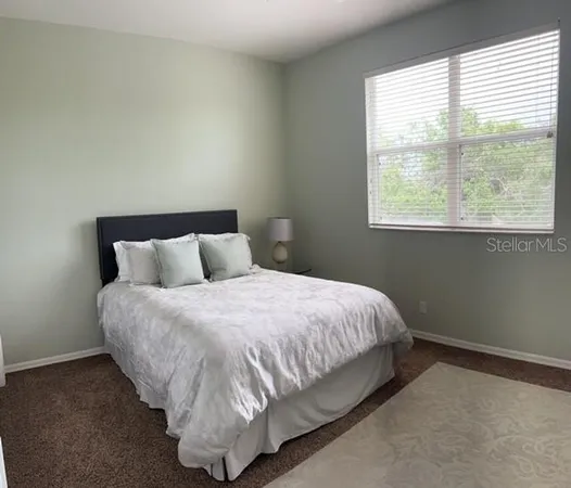 a spacious bedroom with a bed and a flat tv screen on dresser