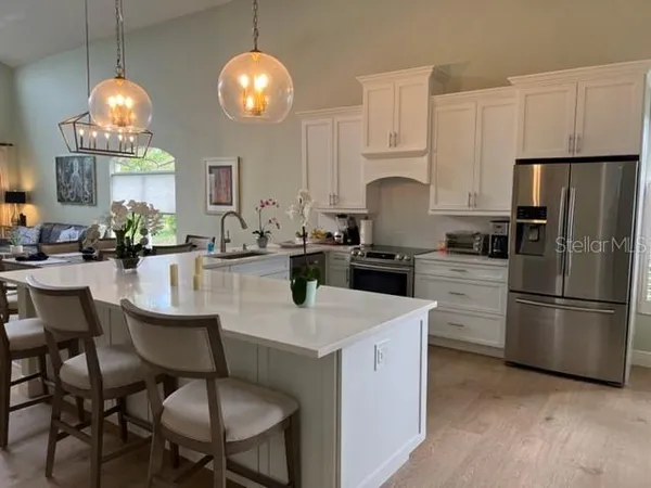a kitchen with sink a refrigerator and chairs