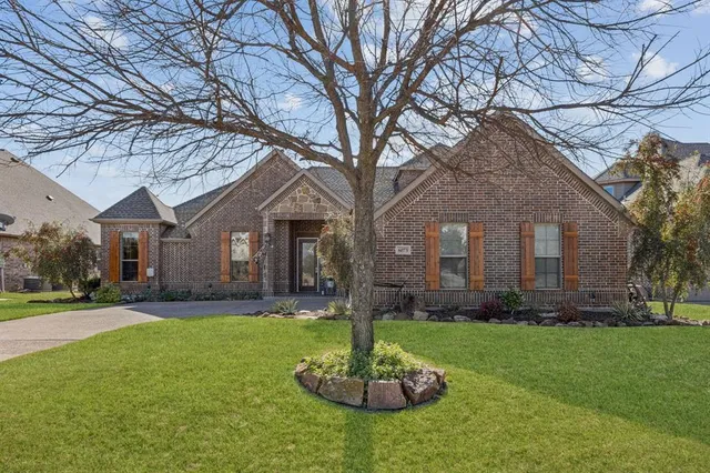 a front view of a house with a yard fire pit and a large tree