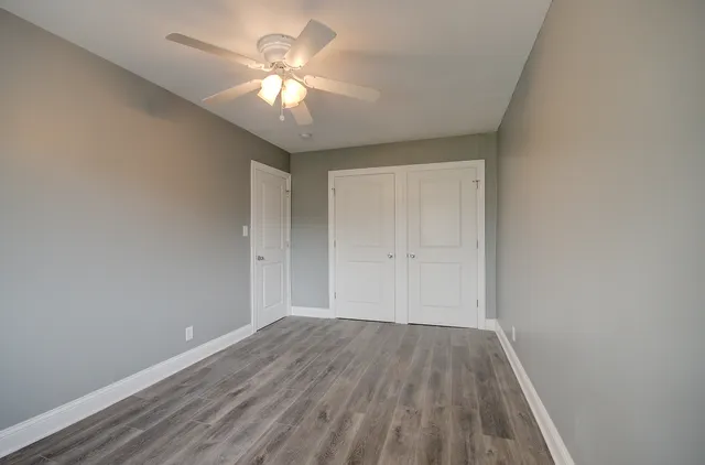 a view of a room with wooden floor and a ceiling fan