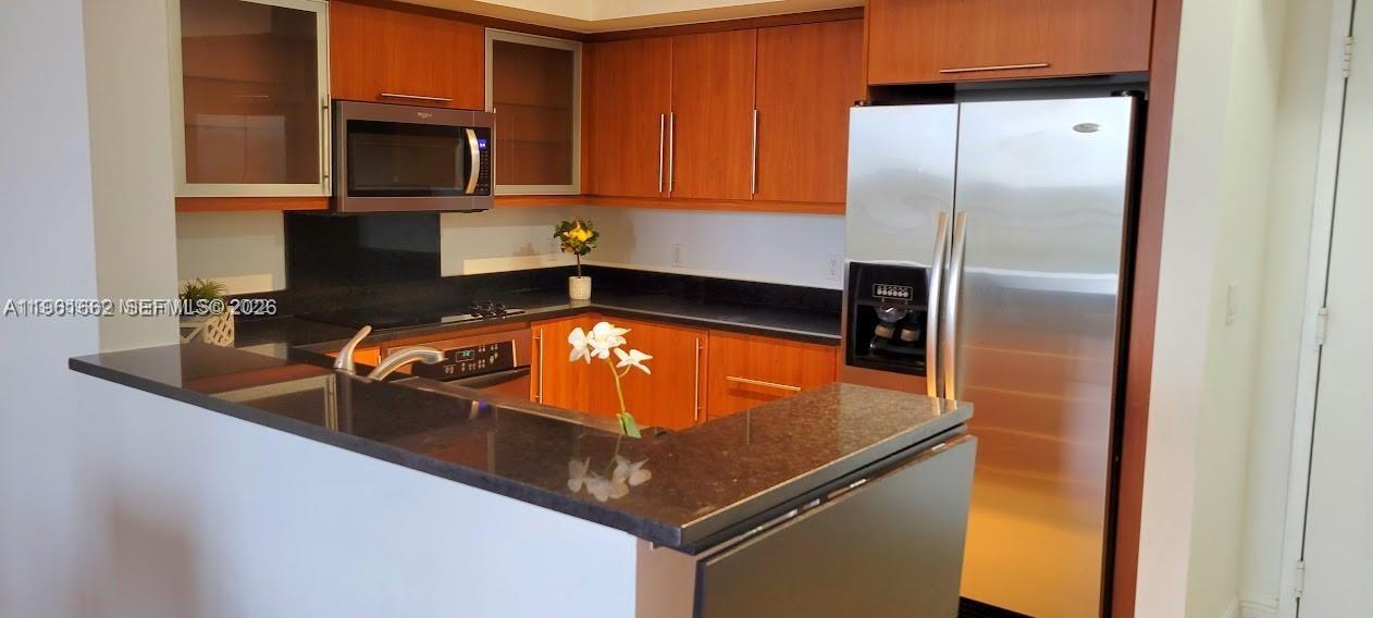 888 Douglas Road, Unit 1401 Coral Gables, FL 33134 - Photo 12 of 43 a kitchen with stainless steel appliances granite countertop a sink a microwave and a refrigerator