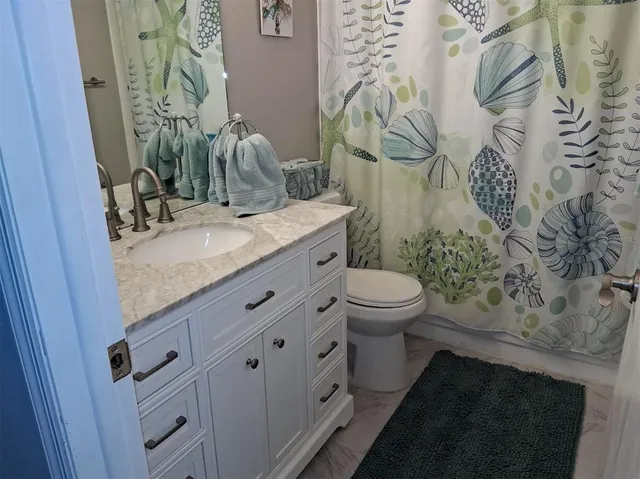a bathroom with a granite countertop sink a toilet and a mirror
