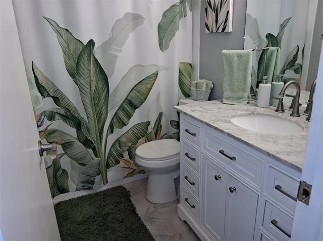 a bathroom with a granite countertop toilet and a sink
