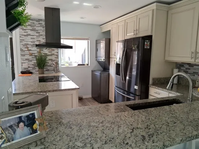 a kitchen with stainless steel appliances granite countertop a refrigerator a stove and a sink