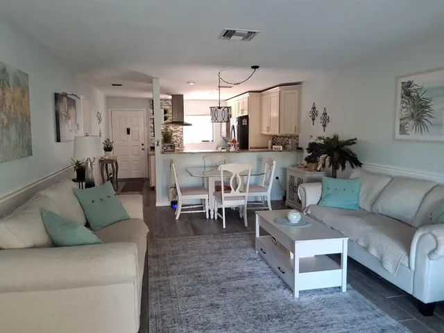 a living room with furniture kitchen view and a chandelier