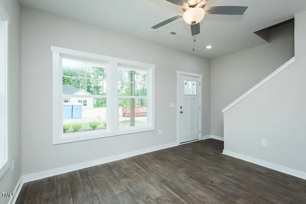 a view of an empty room with wooden floor and a window