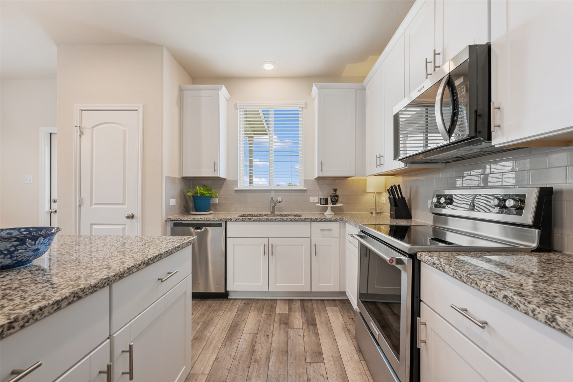 225 Gunther Way Taylor, TX 76574 - Photo 17 of 40 a kitchen with stainless steel appliances granite countertop a stove a sink and a microwave