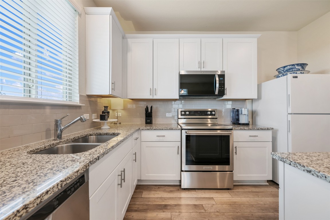 225 Gunther Way Taylor, TX 76574 - Photo 19 of 40 a kitchen with a sink stove and white cabinets