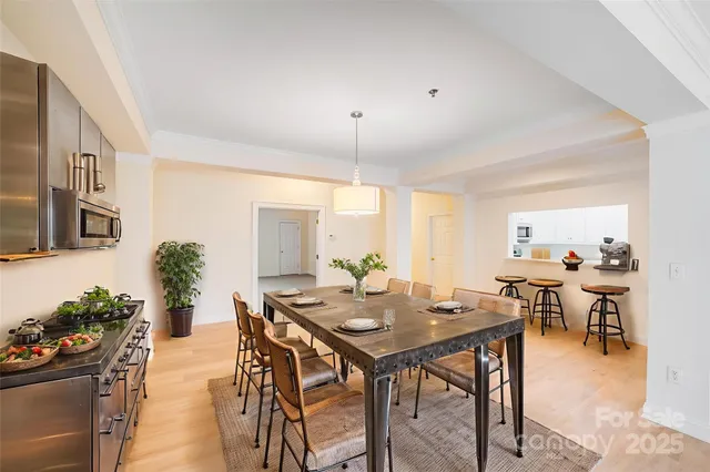 a view of a dining room and livingroom with furniture wooden floor a rug a potted plant and a chandelier