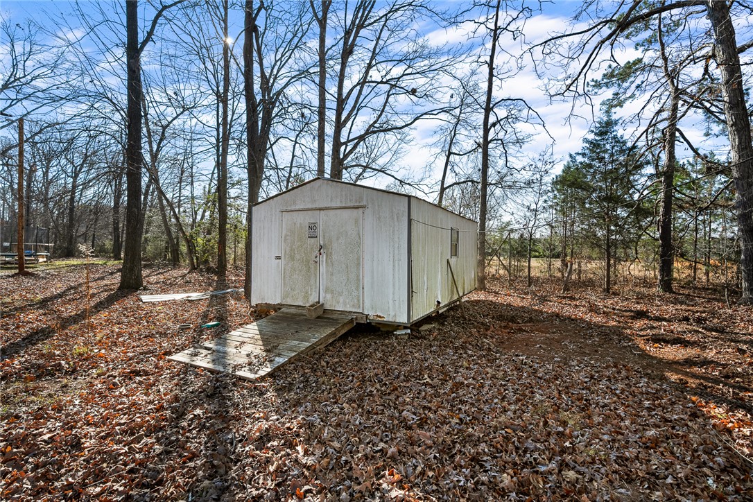 4924 Airline Road Iva, SC 29655 - Photo 32 of 33 A detached shed nestled among trees provides practical outdoor storage and easy access via a wooden ramp.
