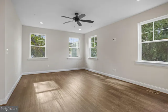 a view of an empty room with a window and wooden floor