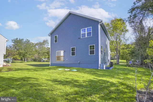 a brick house with a big yard plants and large trees