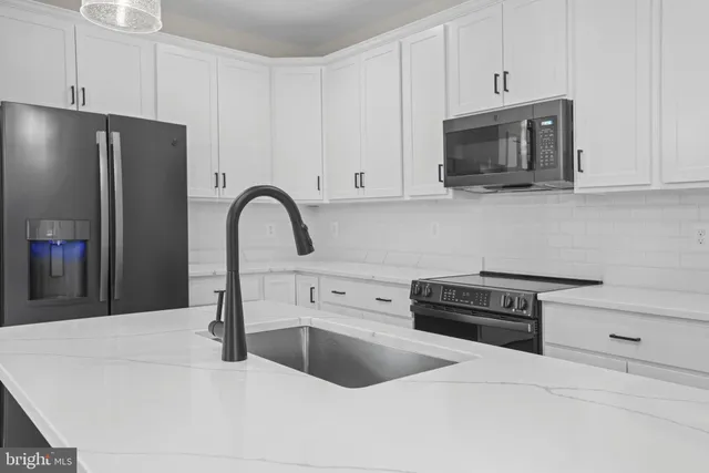 a kitchen with stainless steel appliances granite countertop a sink a stove and a refrigerator with wooden cabinets