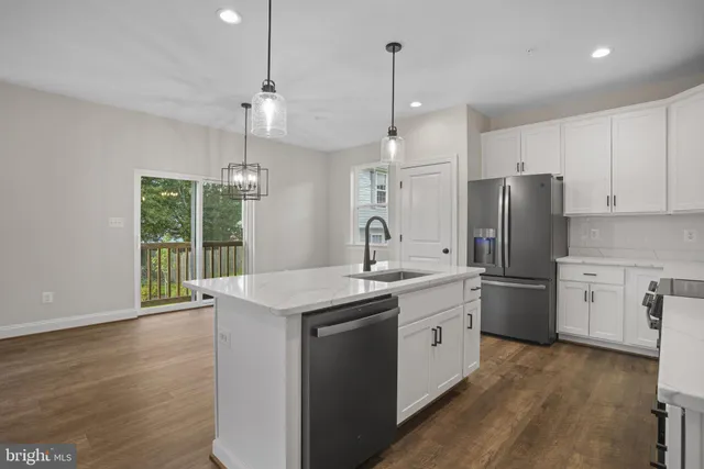 a kitchen with a sink a center island stainless steel appliances and cabinets