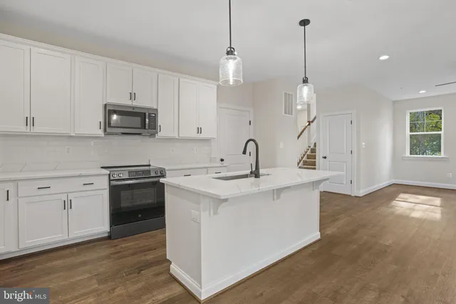 a kitchen with stainless steel appliances granite countertop a sink a stove a refrigerator and island with wooden floor