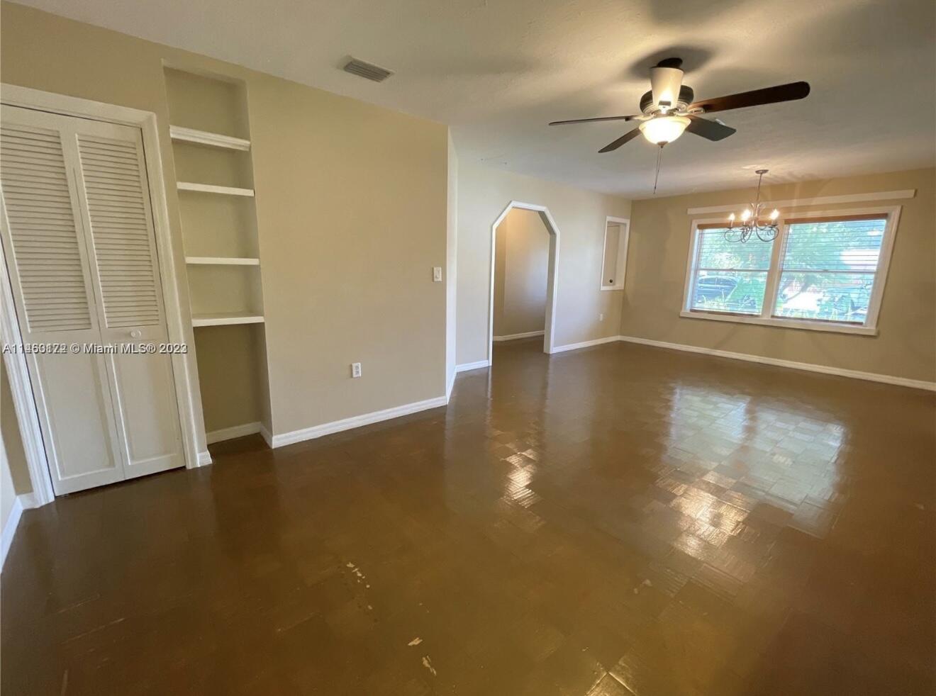 5000 Garner Street, Unit A Fort Pierce, FL 34981 - Photo 4 of 10 an empty room with wooden floor chandelier fan and windows