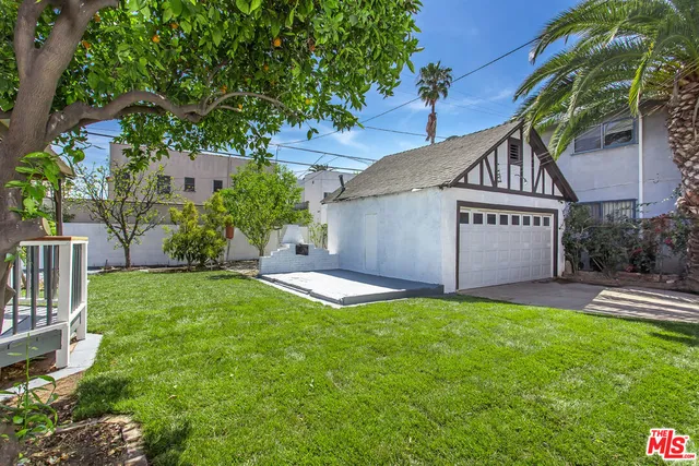 a backyard of a house with plants and large tree
