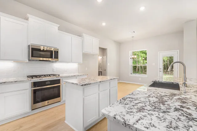 a kitchen with granite countertop cabinets stainless steel appliances and a counter space