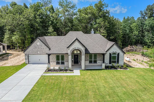 a view of a white house next to a yard and trees