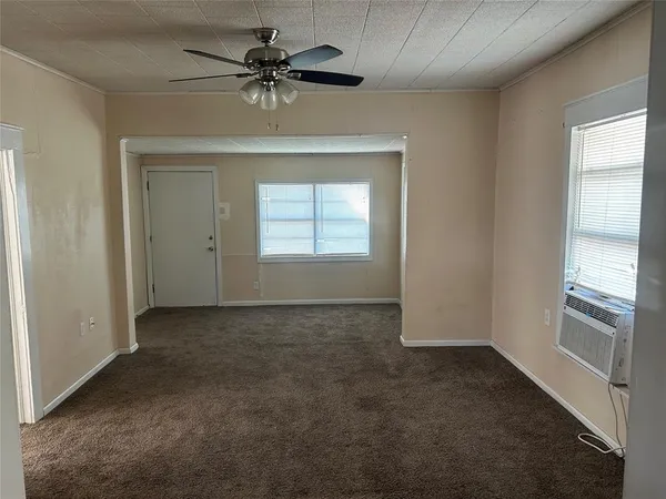 an empty room with a chandelier fan and windows