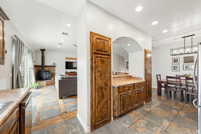 7776 Wagon Road East St. George, UT 84770 - Photo 76 of 76 Kitchen featuring stone tile floors, a wood stove, light countertops, and open floor plan