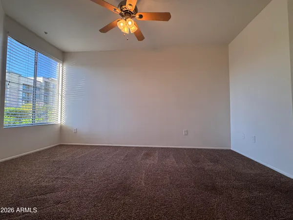 an empty room with windows and chandelier fan