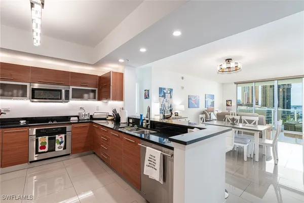 a kitchen with stainless steel appliances granite countertop a stove a sink a refrigerator and white cabinets