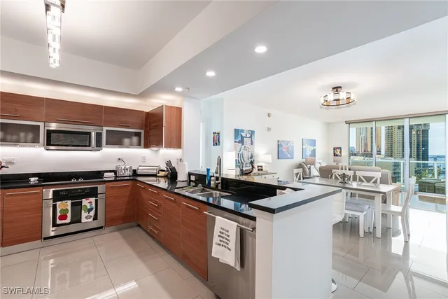 a kitchen with stainless steel appliances granite countertop a stove a sink a refrigerator and white cabinets