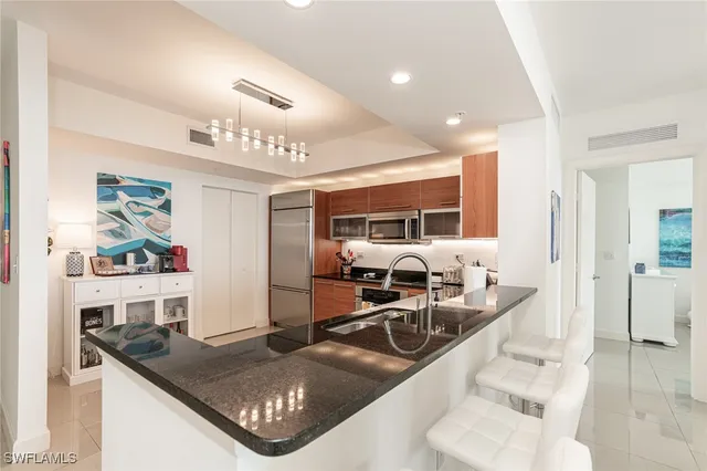 a kitchen with stainless steel appliances granite countertop a sink a counter space and living room view
