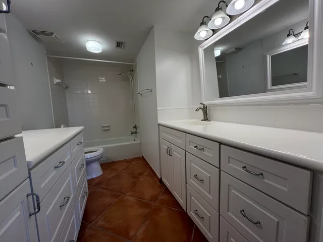 a bathroom with a double vanity sink a toilet a mirror and shower